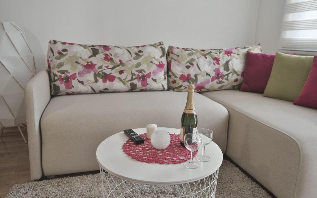 a living room with a couch and a table with a bottle and glasses at Lux Apartman Daria in Zlatibor