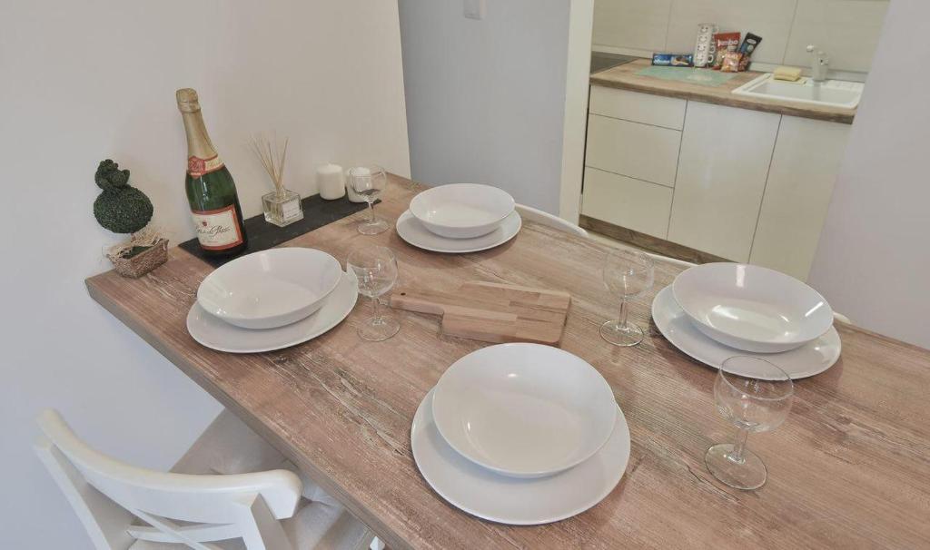 a wooden table with plates and wine glasses on it at Lux Apartman Daria in Zlatibor