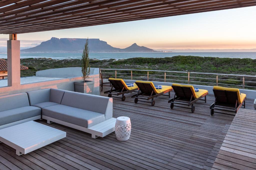 a deck with a couch and chairs and the ocean at Bliss Boutique Hotel in Cape Town