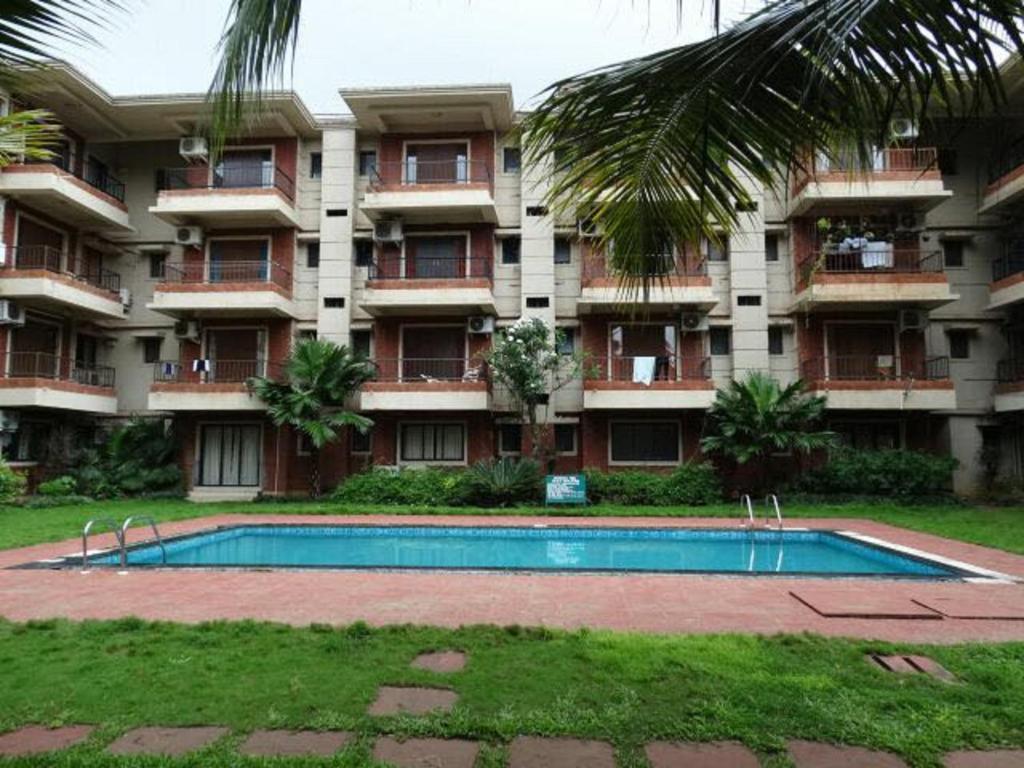 an apartment building with a swimming pool in front of it at Goa Homeland 3 double bed Calangute in Calangute