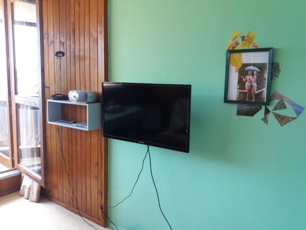ein Flachbildfernseher, der an einer blauen Wand hängt in der Unterkunft studio aux pieds des pistes in Besse-et-Saint-Anastaise