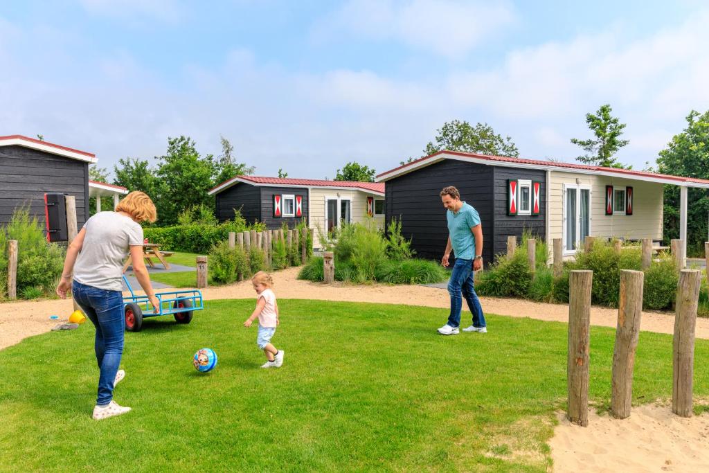 twee volwassenen en een kind spelen met een bal in een tuin bij Camping Ginsterveld in Burgh Haamstede