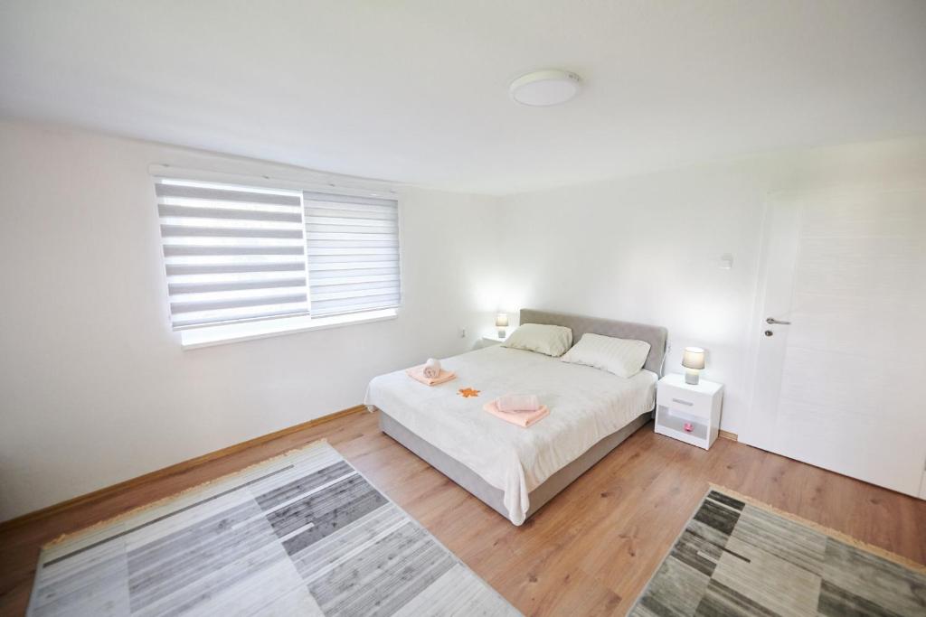 Lovely House Apartment في سراييفو: غرفة نوم بيضاء بها سرير ونافذة