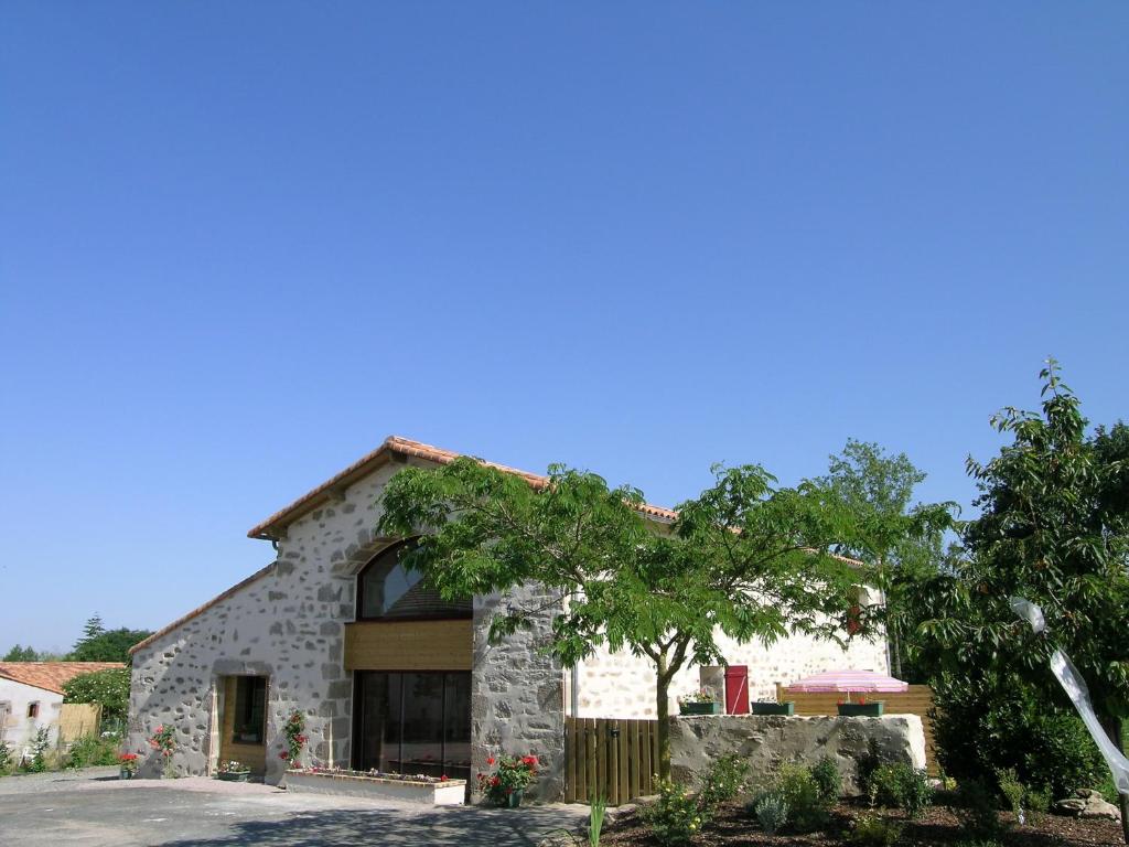 una casa de piedra con un árbol delante en Gîtes " la pagerie" en La Gaubretière
