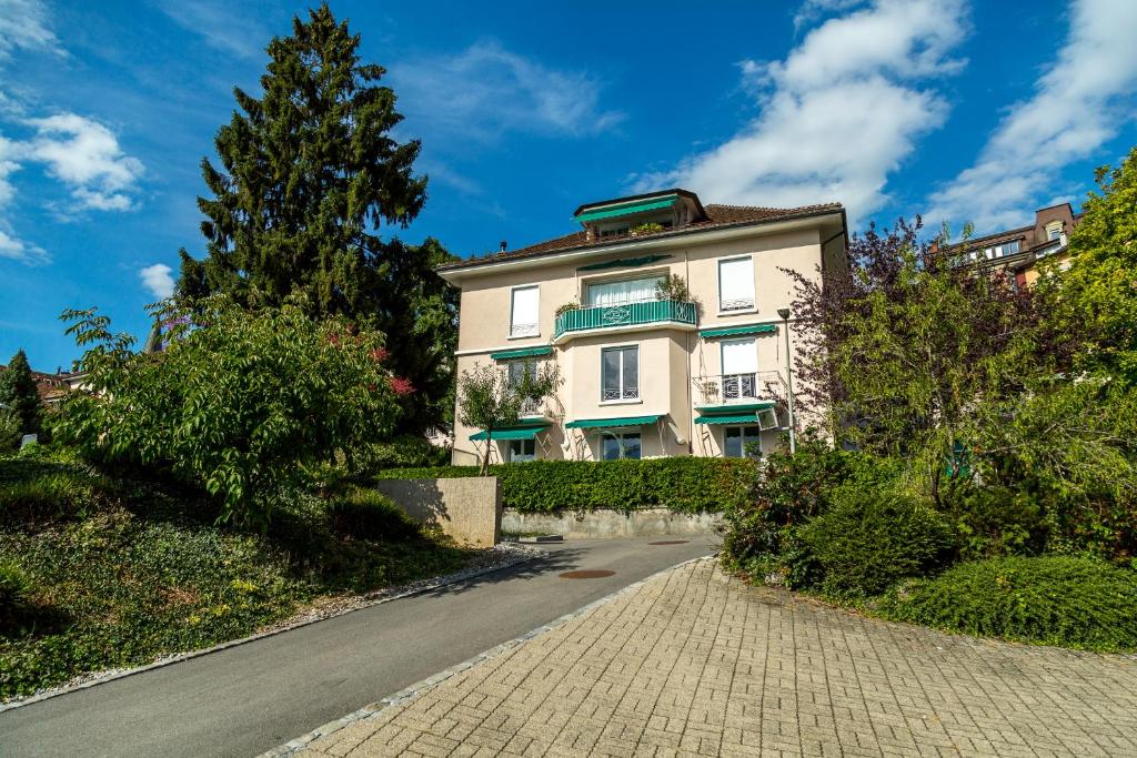 ein großes weißes Gebäude auf einer Straße mit einem Baum in der Unterkunft Les Amandiers in Montreux