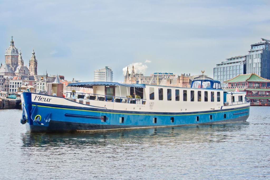 un barco azul y blanco sentado en el agua en Hotelboat Fleur, en Ámsterdam