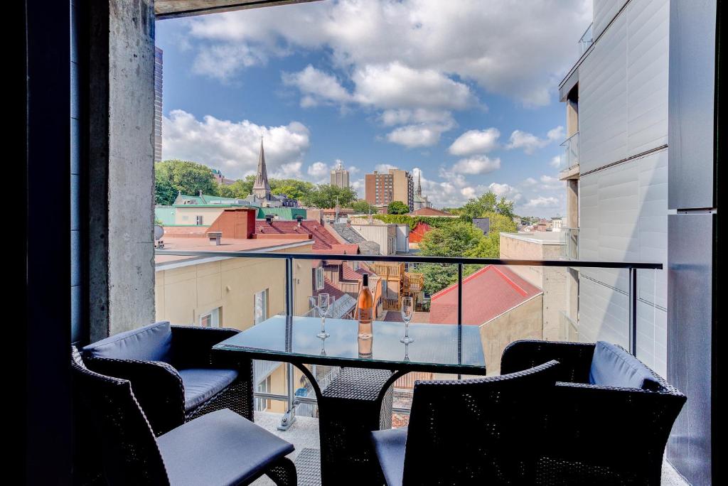 a table on a balcony with a view of a city at Les Immeubles Charlevoix - Le 760504 in Quebec City