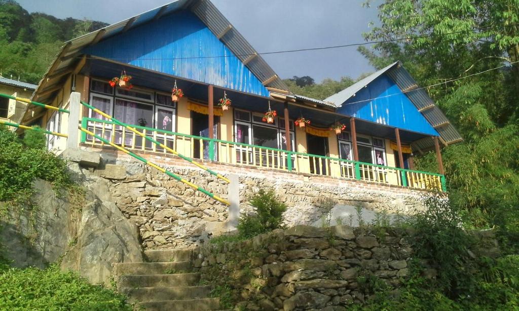 a house with a blue roof on a mountain at Vamoose Tashi Homestay in Rangpo