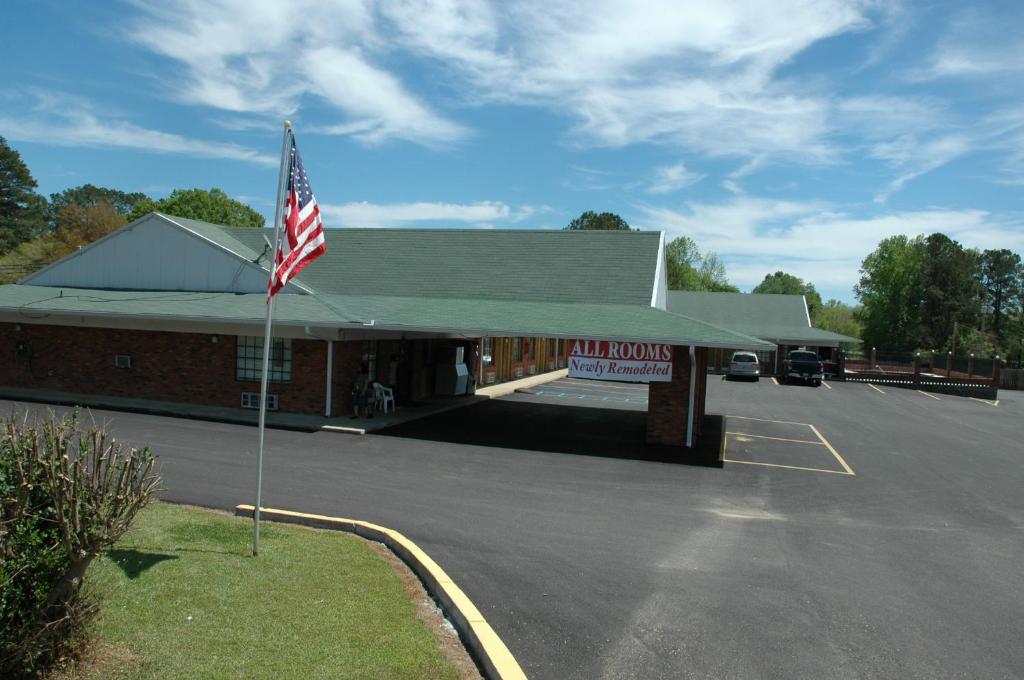 un edificio con una bandera americana en un estacionamiento en Western Motel - Prentiss, en Prentiss