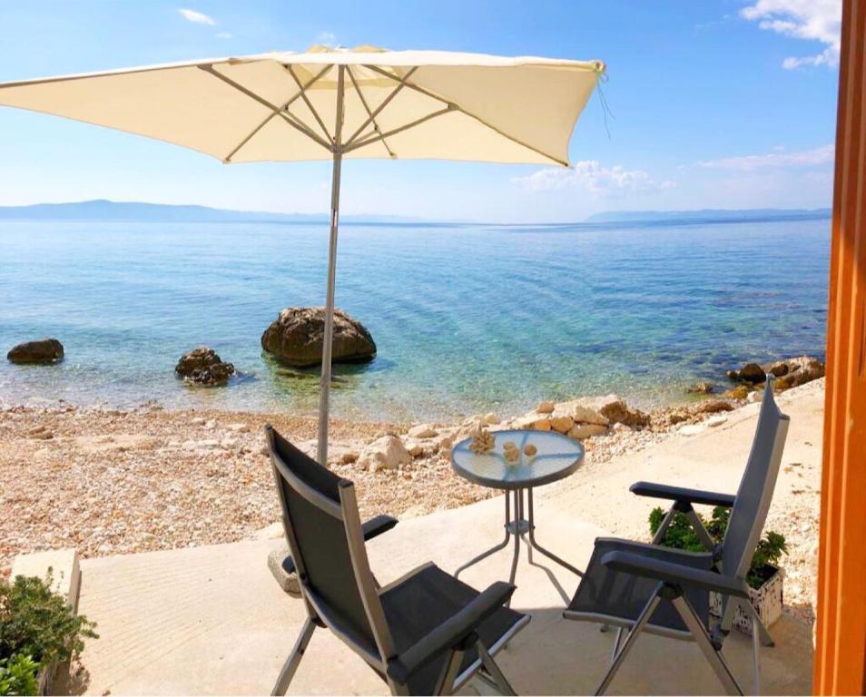 a table and two chairs and an umbrella on a beach at Apartment Marina in Drasnice