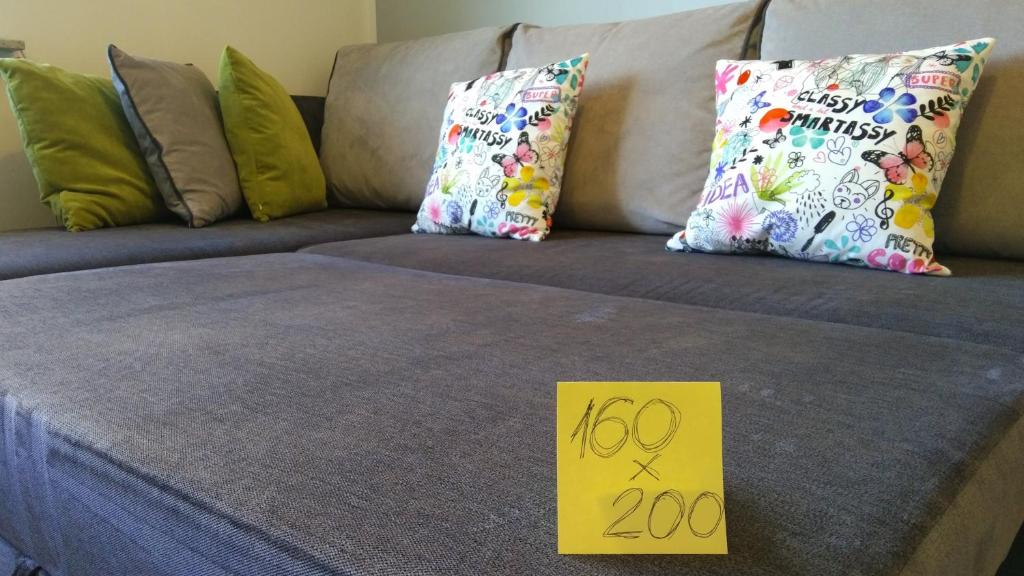 a yellow sign sitting on top of a couch with pillows at Apartamenty Słupsk in Słupsk