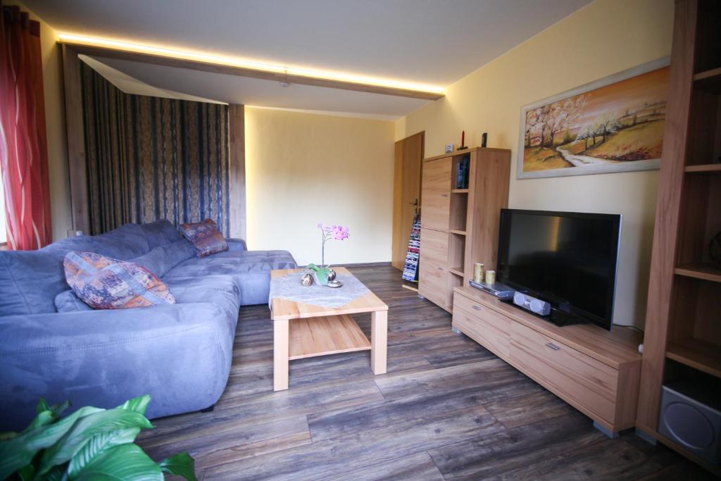 a living room with a blue couch and a table at Ferienwohnung Estel in Bärenstein