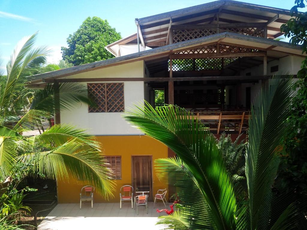 ein gelbes und weißes Gebäude mit Stühlen davor in der Unterkunft Pagalù Hostel in Puerto Viejo