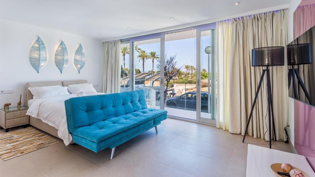 a bedroom with a blue couch and a large window at The Hype Beachhouse in Playa de Palma