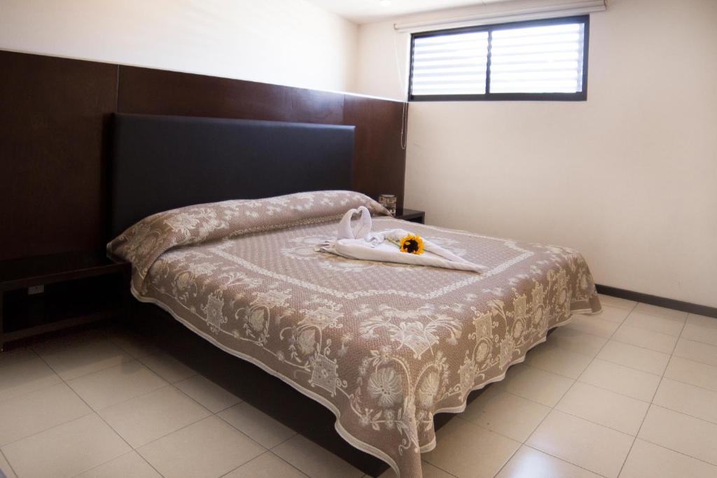 Una cama con una bandeja con una flor. en Hotel Ross, en Morelia
