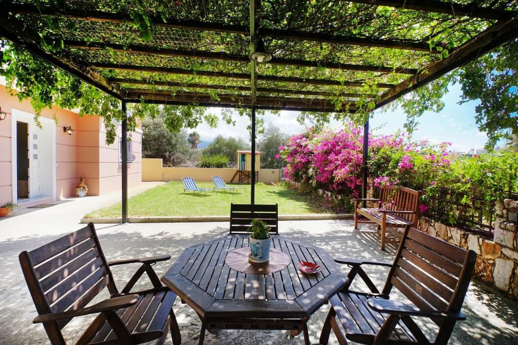 een patio met een tafel en stoelen en een pergola bij Maria's Garden in Galatás