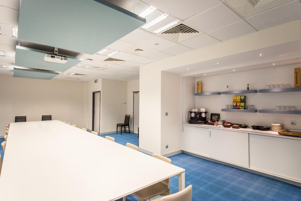 an office with a table and chairs and a kitchen at Mandarina Hotel Luxembourg Airport in Luxembourg