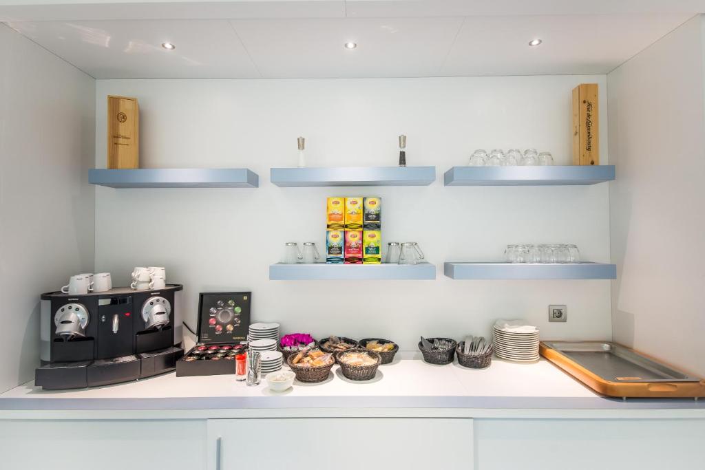 a kitchen with a counter with dishes and a stove at Mandarina Hotel Luxembourg Airport in Luxembourg