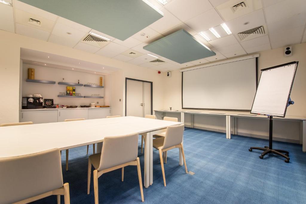 a conference room with a table and chairs and a whiteboard at Mandarina Hotel Luxembourg Airport in Luxembourg
