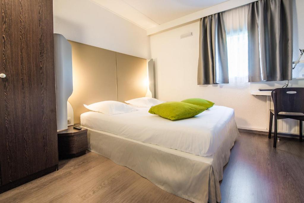 a bed room with a white bedspread and pillows at Mandarina Hotel Luxembourg Airport in Luxembourg