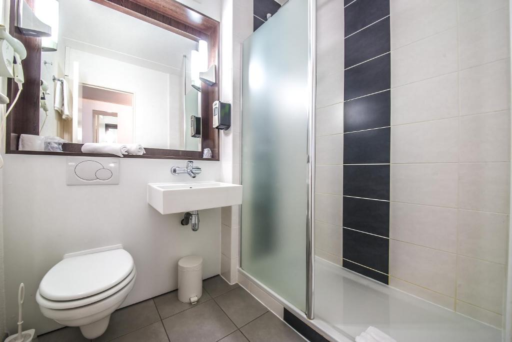 a bathroom with a toilet and a sink and a shower at Mandarina Hotel Luxembourg Airport in Luxembourg