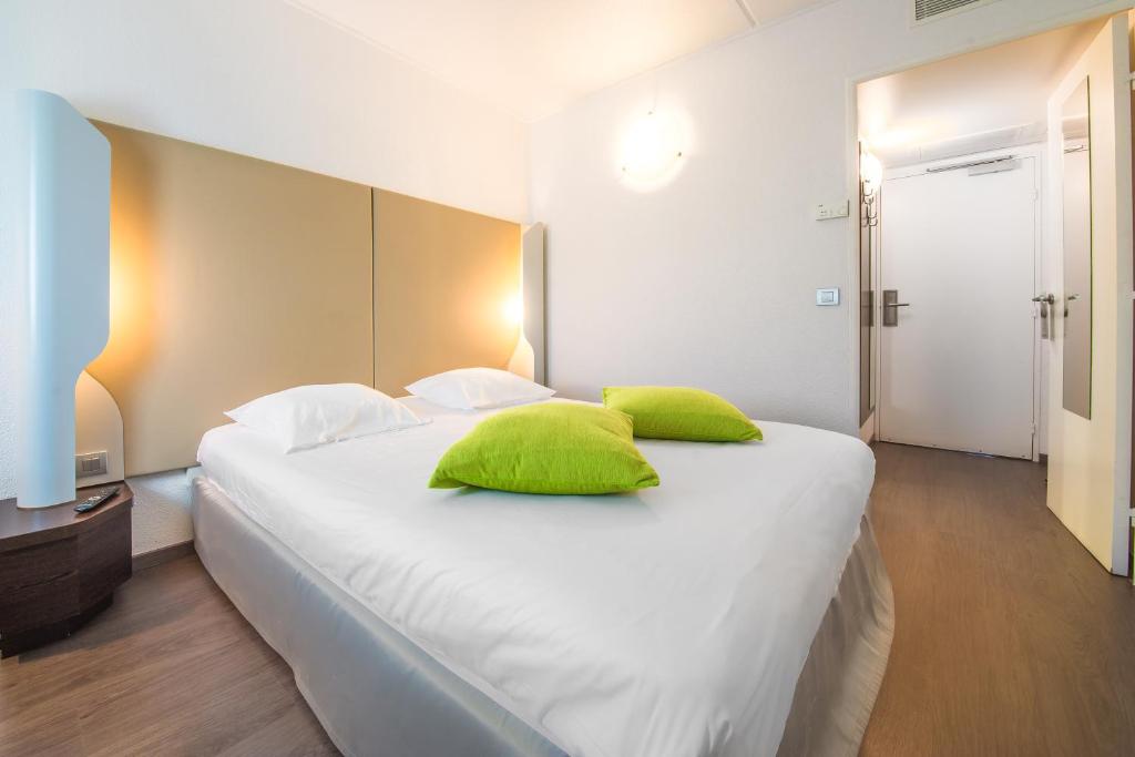 a bedroom with a white bed with green pillows at Mandarina Hotel Luxembourg Airport in Luxembourg