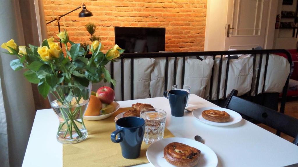 a table with plates of food and a vase of flowers at Apartment Úvoz Street 64 in Brno
