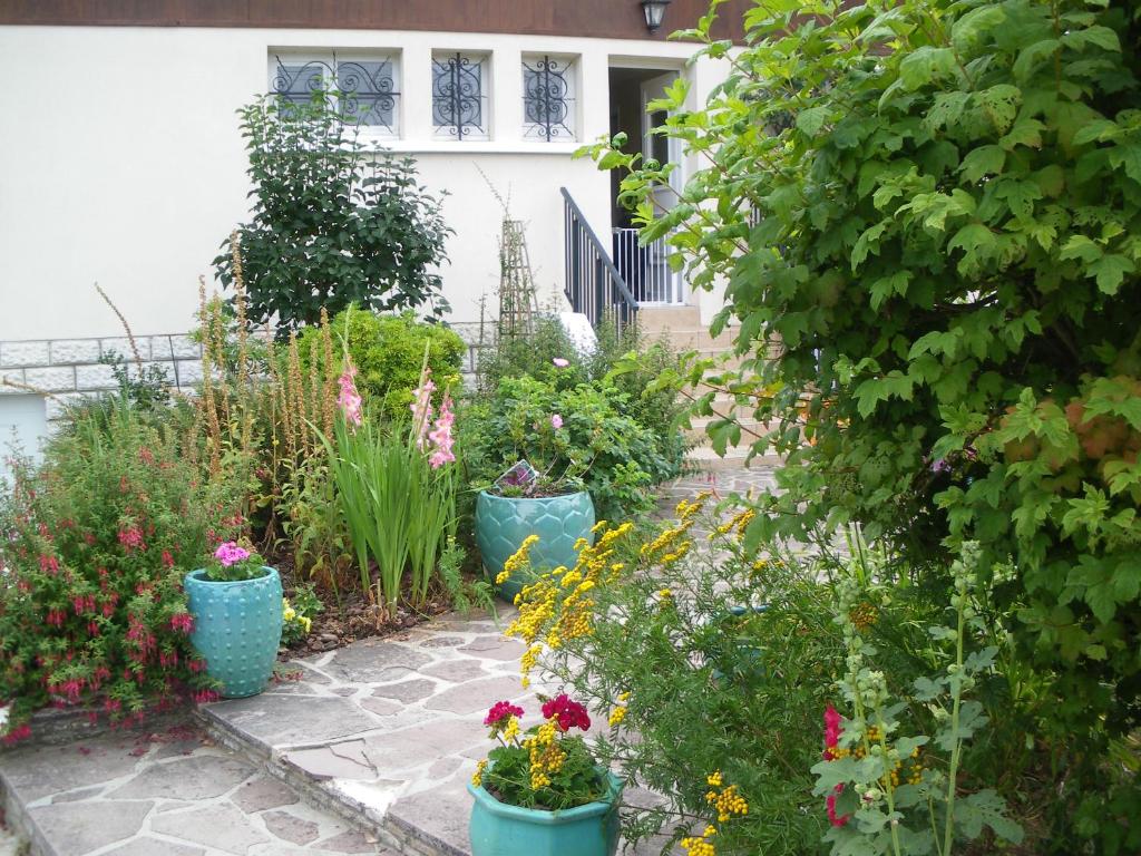 un jardín con flores y plantas en cubos en Chambre d'Hôtes - DOUCE NUI-THE en Vernouillet