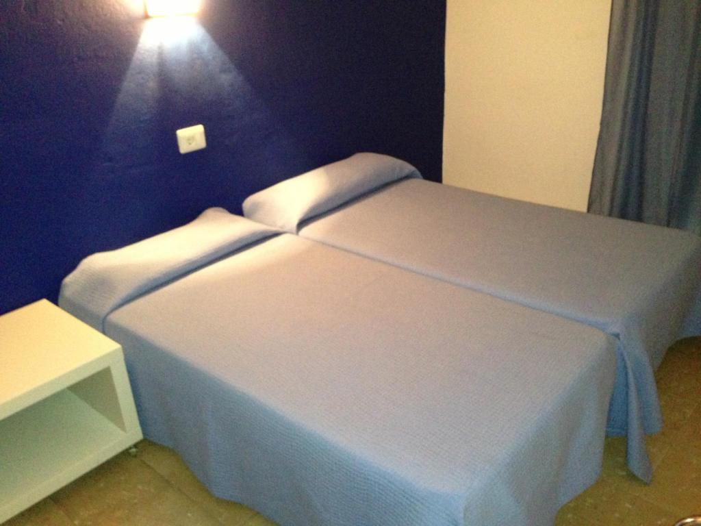 um quarto com uma cama branca e uma luz na parede em Hostal German em Port de la Selva