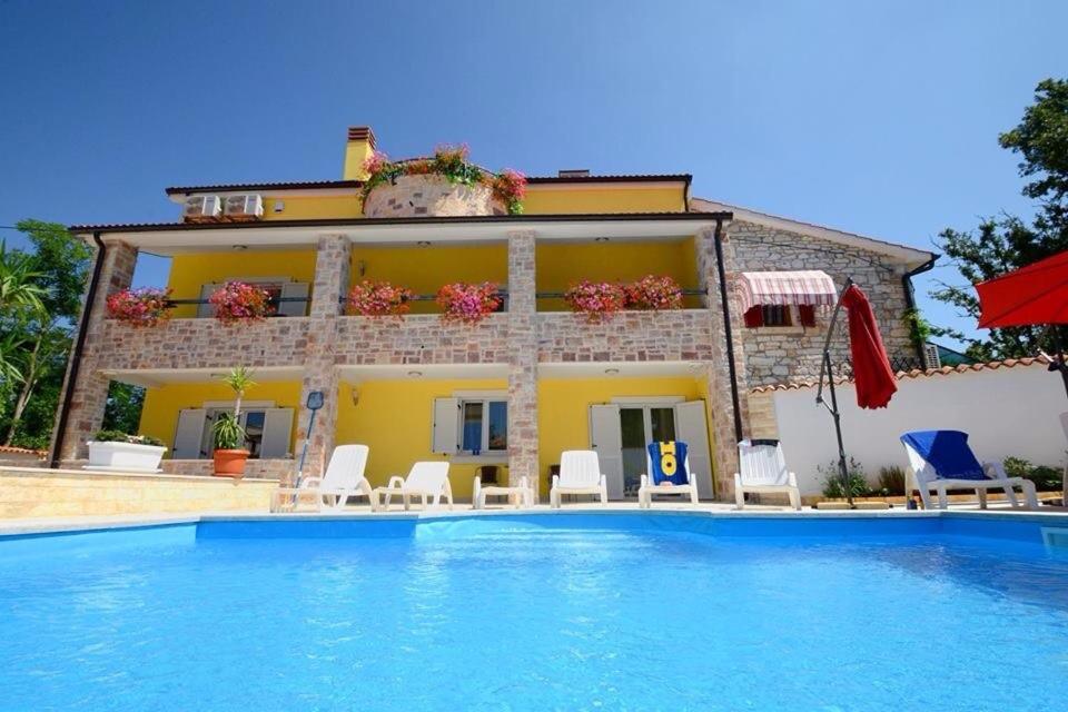 a villa with a swimming pool in front of a house at Apartments Villa Mimi in Višnjan