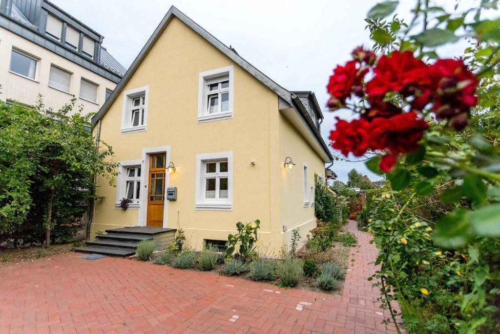 une maison jaune avec des fleurs rouges devant elle dans l'établissement finkeshaus, à Lüdinghausen