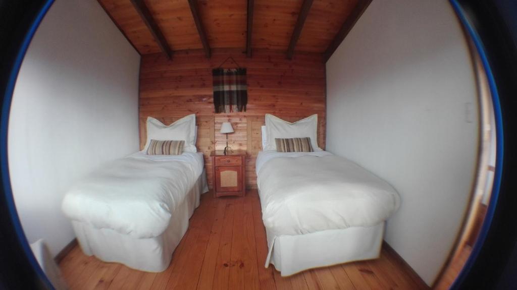 two beds in a room with a mirror at Terrazas del Palena in La Junta
