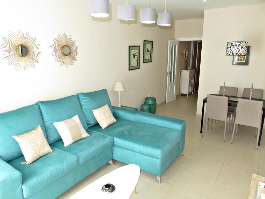 a living room with a blue couch and a dining room at Apartamento barrio San Miguel in Jerez de la Frontera
