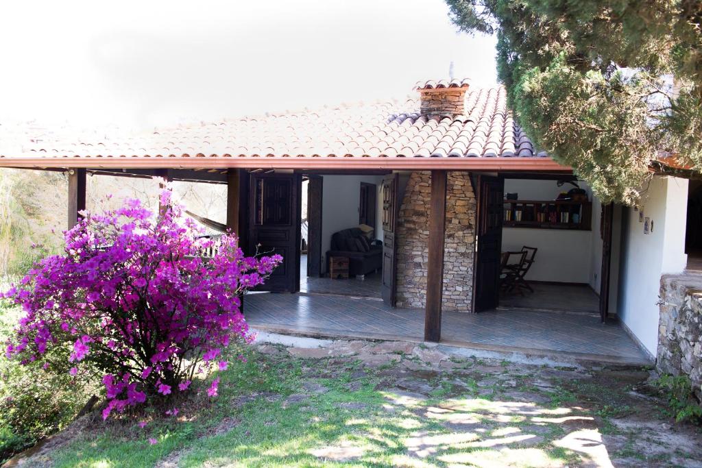 uma casa com um alpendre com flores roxas em Sossego e aconchego ao lado do INHOTIM em Brumadinho