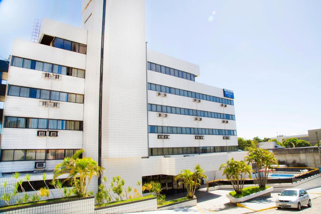 un bâtiment blanc avec des palmiers devant lui dans l'établissement Monza Palace Hotel, à Natal