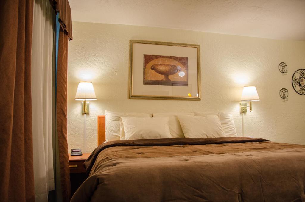 ein Hotelzimmer mit einem Bett mit zwei Lampen und einem Bild in der Unterkunft Budget Inn &amp; Suites Colby in Colby