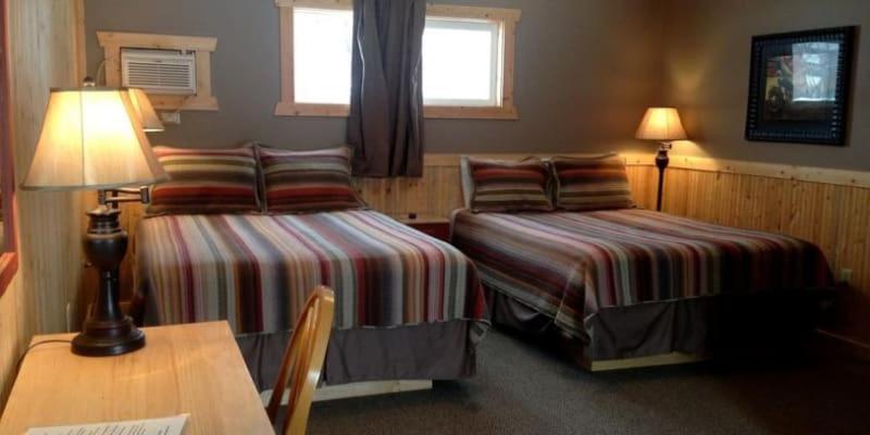 una camera d'albergo con due letti e un tavolo con una lampada di Red Lodge Inn a Red Lodge