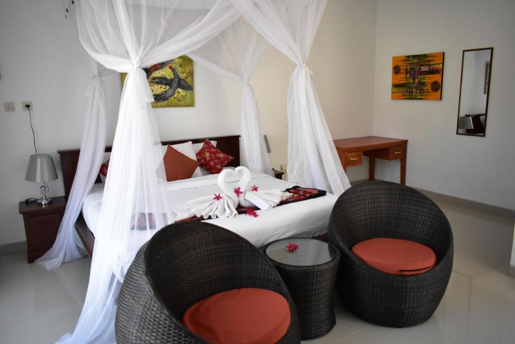 a bedroom with a bed with two wicker chairs at The Barari Villas in Pemuteran