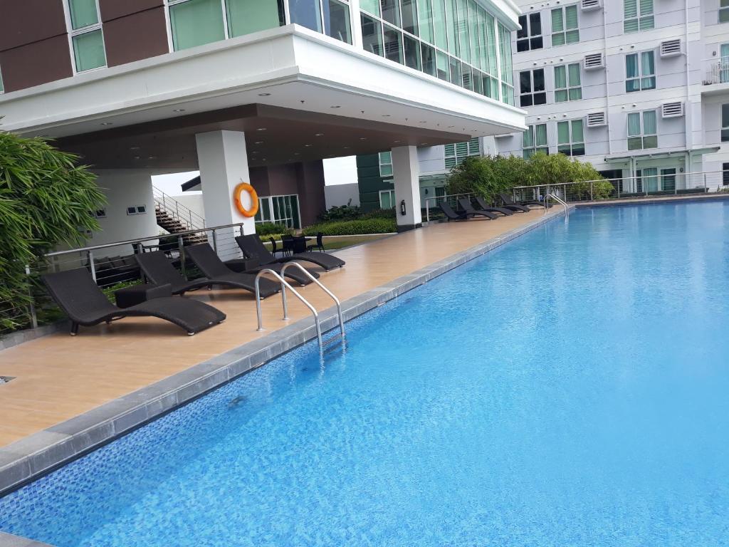 a large swimming pool with chairs and a building at Abreeza Place by Chriza in Davao City