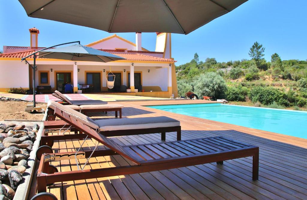 a house with a swimming pool and an umbrella at Monte do Pego in Arneiro