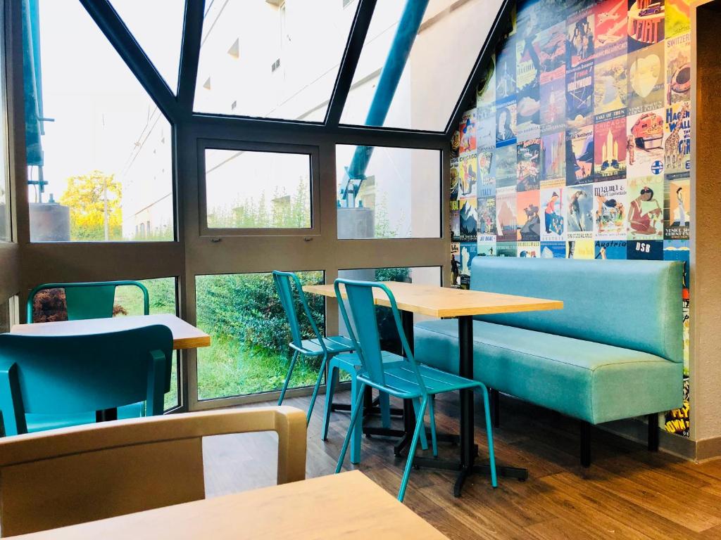 um restaurante com cadeiras e mesas azuis e uma janela em hotelF1 Genève Aéroport Ferney em Ferney-Voltaire
