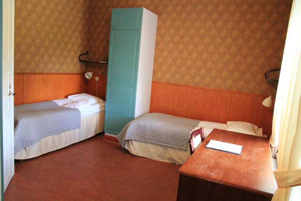 a hotel room with two beds and a desk with a desk at Savonlinnan Kansanopisto - Wanha Pappila in Savonlinna