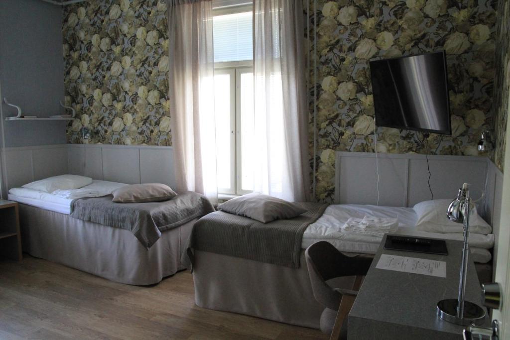 a room with two beds and a television on the wall at Savonlinnan Kansanopisto - Wanha Pappila in Savonlinna