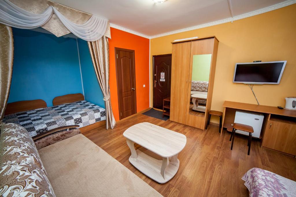 een kamer met 2 bedden, een tv en een bureau bij Dubrava Hotel in Kazan