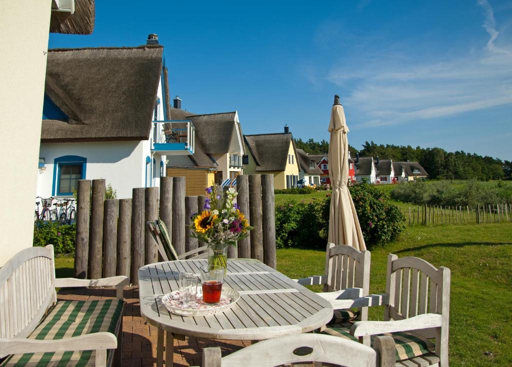 a table and chairs with a vase of flowers and an umbrella at Ferienhaus - Huus Holm in Breege