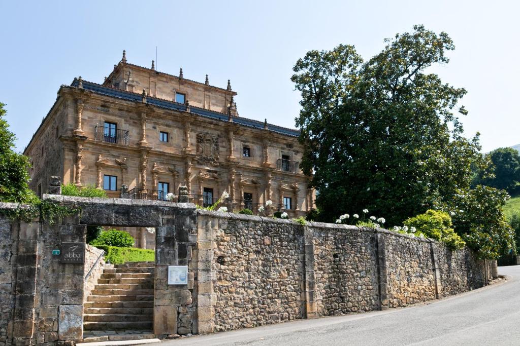 un antiguo edificio de piedra en una pared con escaleras en Abba Palacio de Soñanes Hotel, en Villacarriedo