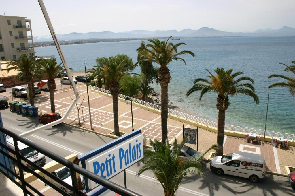 uma vista para uma rua com palmeiras e o oceano em Petit Palais Hotel em Loutraki