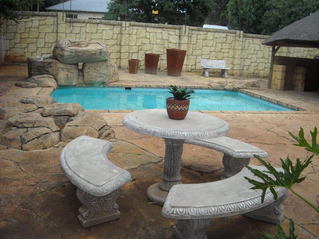 una mesa y dos sillas frente a una piscina en Upper Houghton Guesthouse, en Johannesburgo