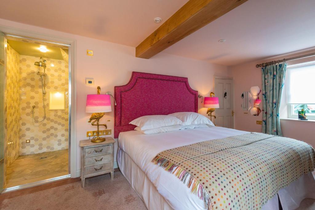 um quarto com uma cama grande e uma cabeceira de cama roxa em Devonshire Arms at Beeley - Chatsworth em Beeley
