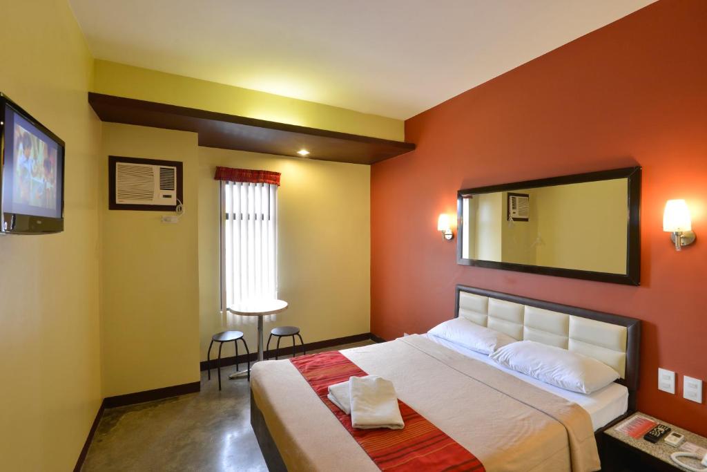 a bedroom with a large bed and a mirror at Express Inn Cebu Mabolo in Cebu City